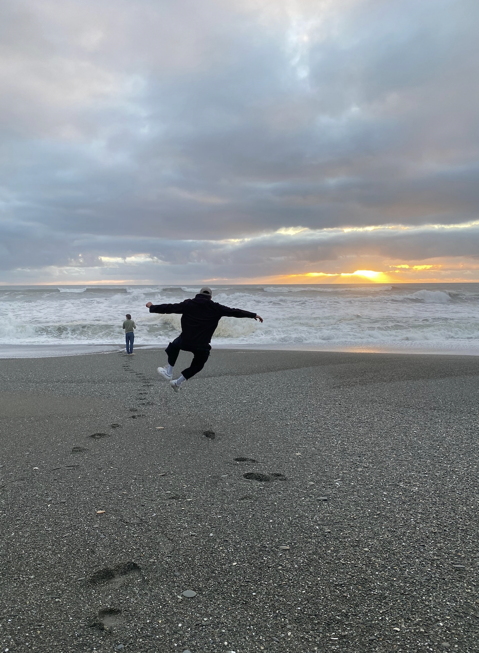 Reuben jumping on the beach at sunset in New Zealand